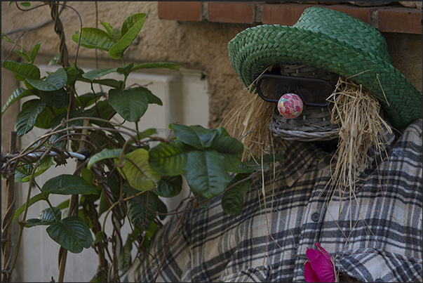 Scarecrows sitting in windows also adorn the facades of houses